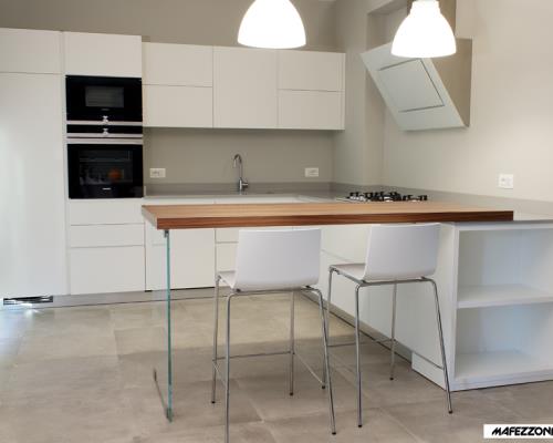 Cucina moderna in laminato bianco con antine smussate a 30° senza maniglie. Esempio di una cucina in stile minimale.