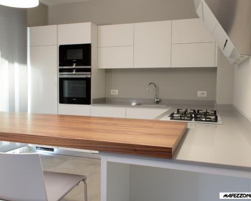 Cucina moderna in laminato bianco con antine smussate a 30° senza maniglie.